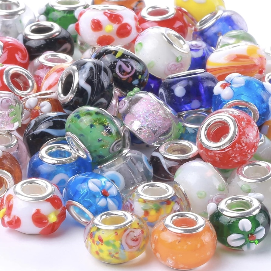 A pile of colorful glass beads with silver-lined holes, featuring patterns like flowers, swirls, and dots in vibrant hues—perfect for beaded garden stakes DIY projects.